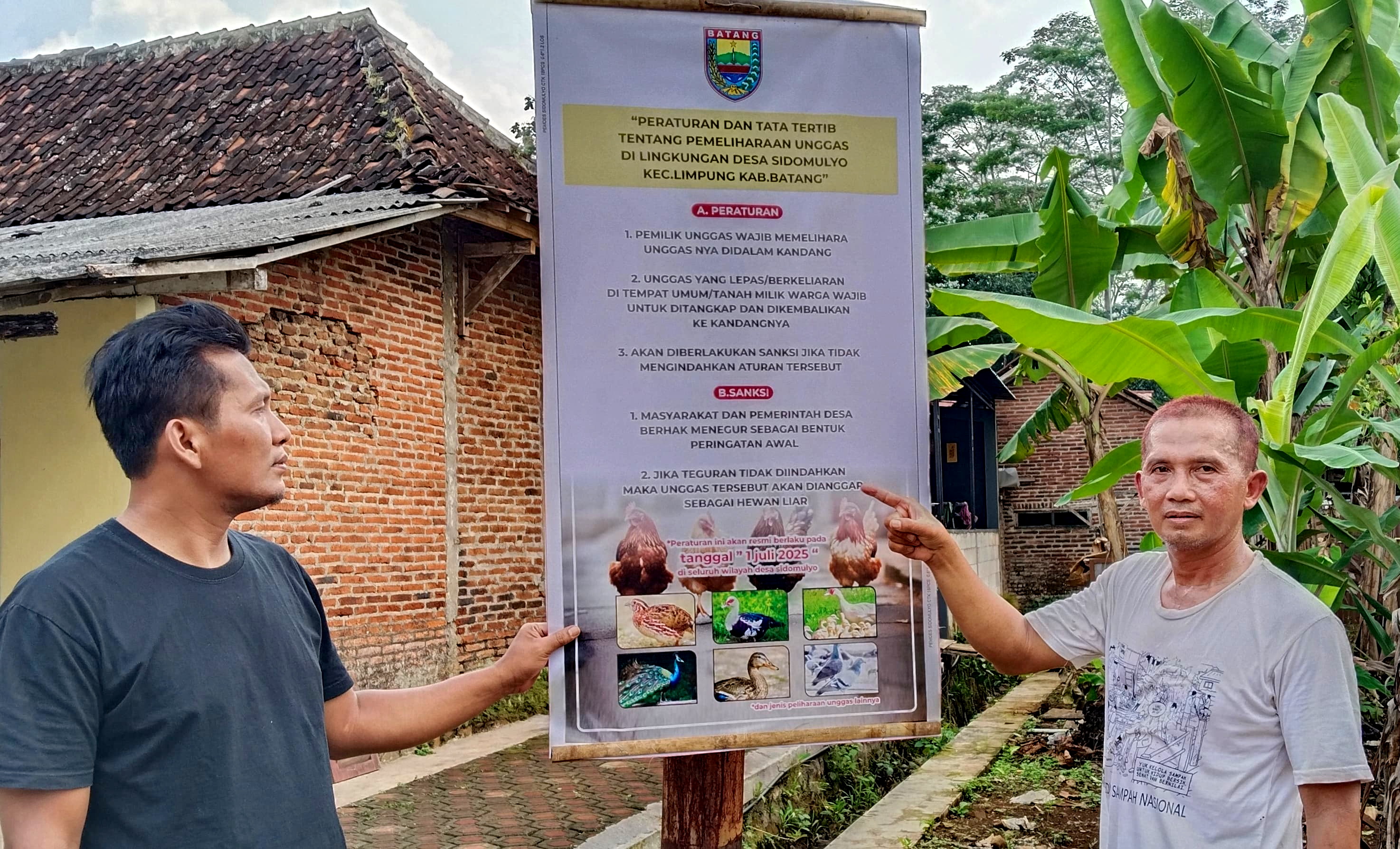 TUNJUKKAN PAPAN PENGUMUMAN - Kades Sidomulyo Kecamatan Limpung Faisol Al Jupri (kaos putih) menunjukkan Perdes, yang disebar di beberapa lokasi di Desa setempat, Jumat (4/7/2025).