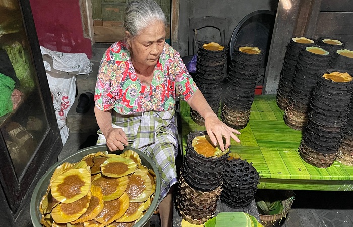 PRODUKSI APEM : Mak Menis yang mewarisi resep turun temurun ini dengan telaten membuat apem Kesesi, Senin (21/7/2025).