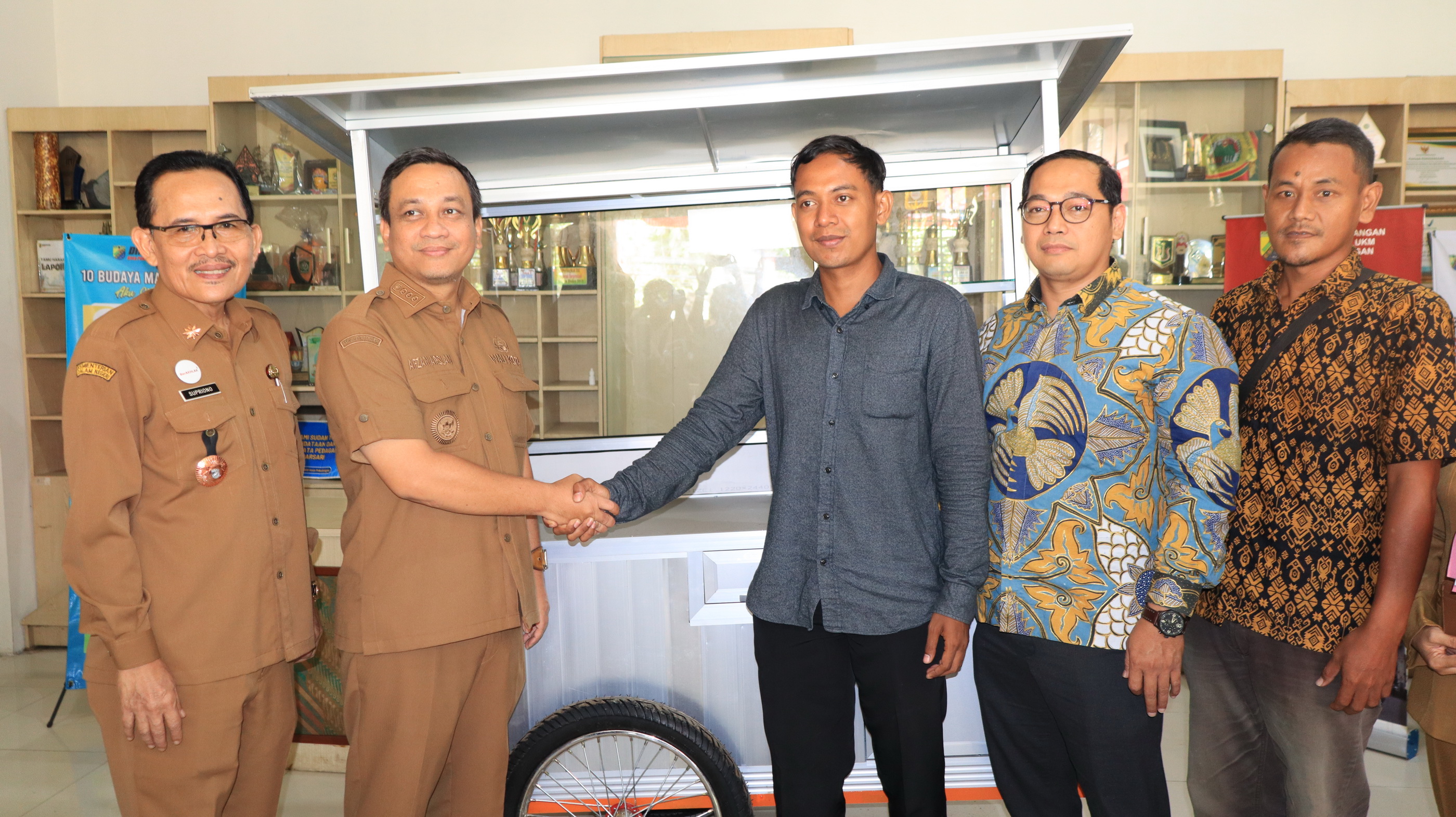 SERAHKAN &ndash; Salah satu penerima bantuan gerobak usaha, saat menerima langsung dari Walikota Pekalongan dan anggota DPRD Kota Pekalongan, Nasrullah, di kantor Dindagkop-UKM setempat, Senin (4/8/2025).