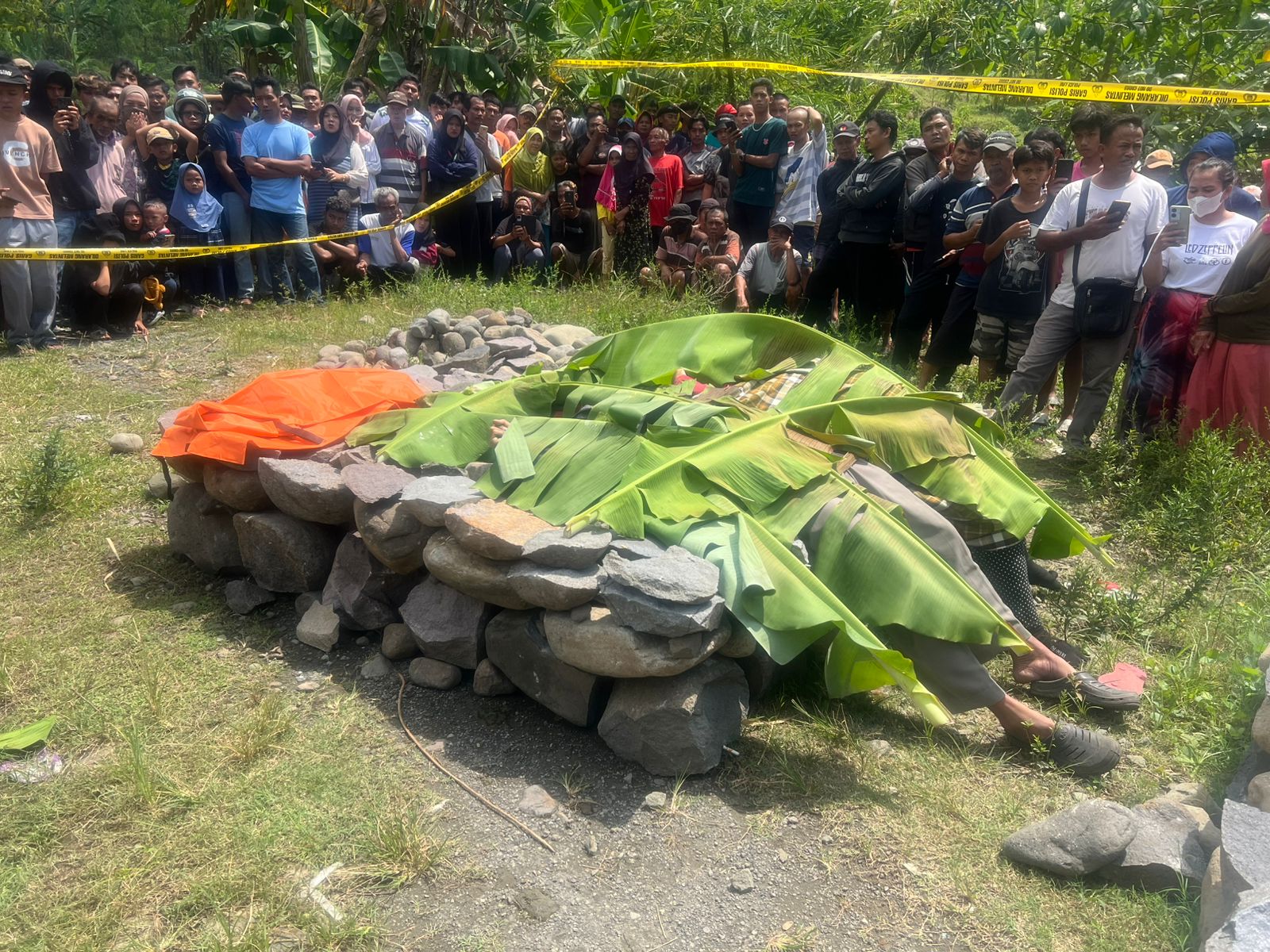 BERKERUMUN - Warga berkerumun i lokasi penemuan jasad sepasang suami istri, di tepi sungai Desa Mereng, Kecamatan Warungpring Pemalang, Minggu (10/8/2025).