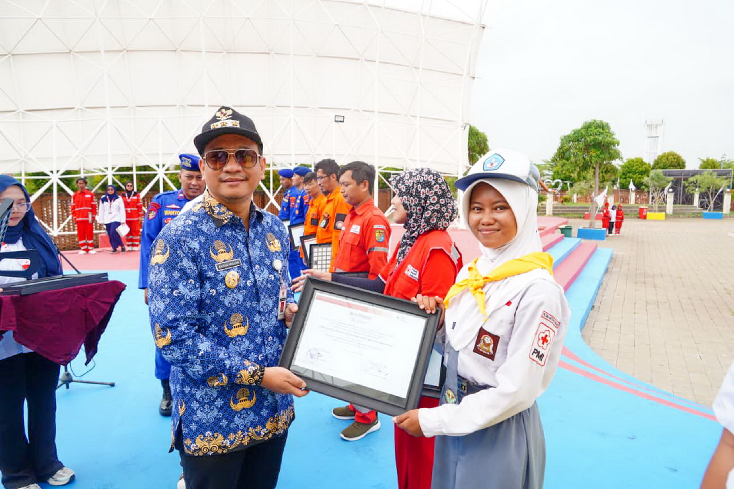 PENGHARGAAN - Wali Kota Pekalongan, HA Afzan Arslan Djunaid saat serahkan penghargaan kepada salah satu anggota PMR setempat yang berprestasi, saat apel peringatan HUT PMI di TWL, Rabu (17/9/2025).