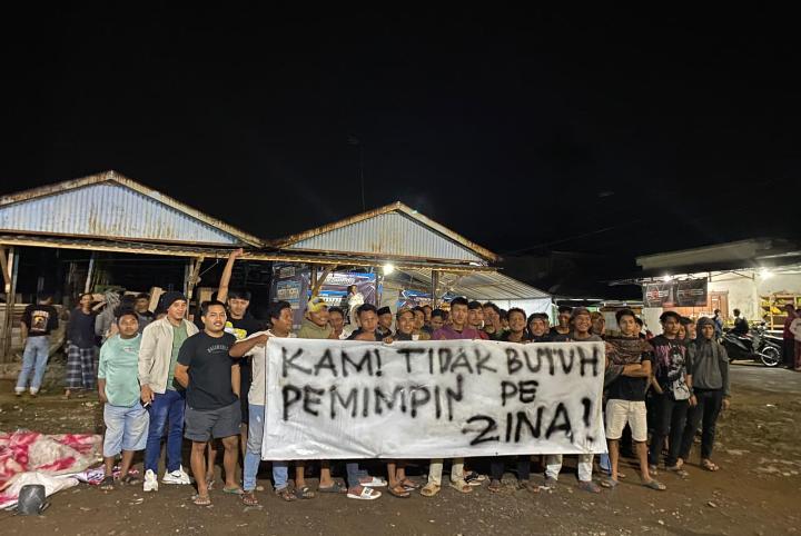 PROTES: Warga membentangkan poster protes terhadap kadesnya yang sebelumnya digrebek di rumah warganya.