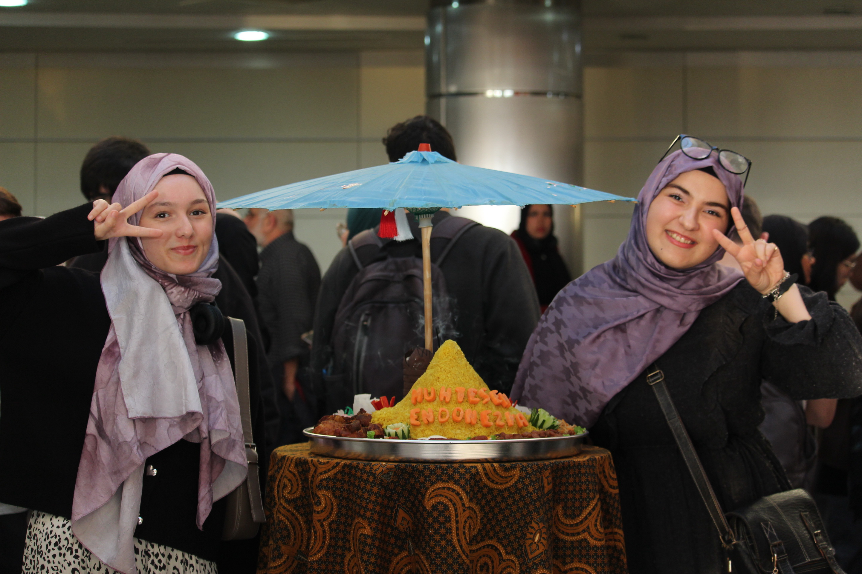 Pengunjung perempuan dari Turki berfoto bersama tumpeng khas Indonesia, menandai antusiasme masyarakat lokal terhadap kekayaan kuliner Nusantara_