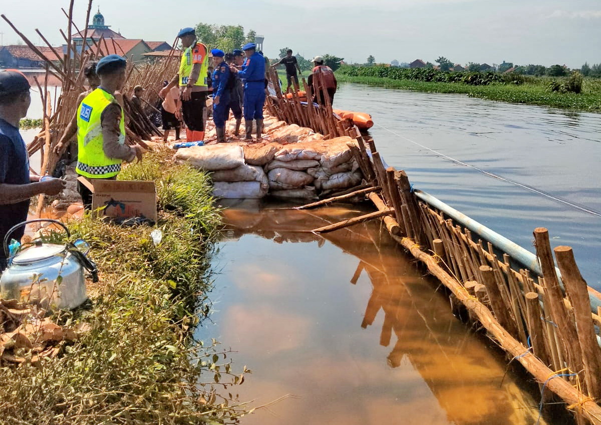 BANGUN TANGGUL - Tim gabungan dari berbagai unsur dan masyarakat, saat membangun tanggul darurat di Pabean, pada Kamis (8/1/2026).