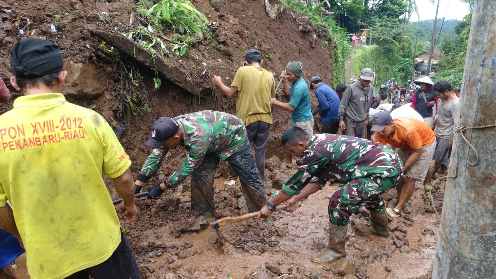 LONGSOR: Warga besama TNI kerja bakti membersihkan material longsor di jalan utama Desa Pugangan, Doro, Kabupaten Pekalongan, Minggu (18/1/2026).
