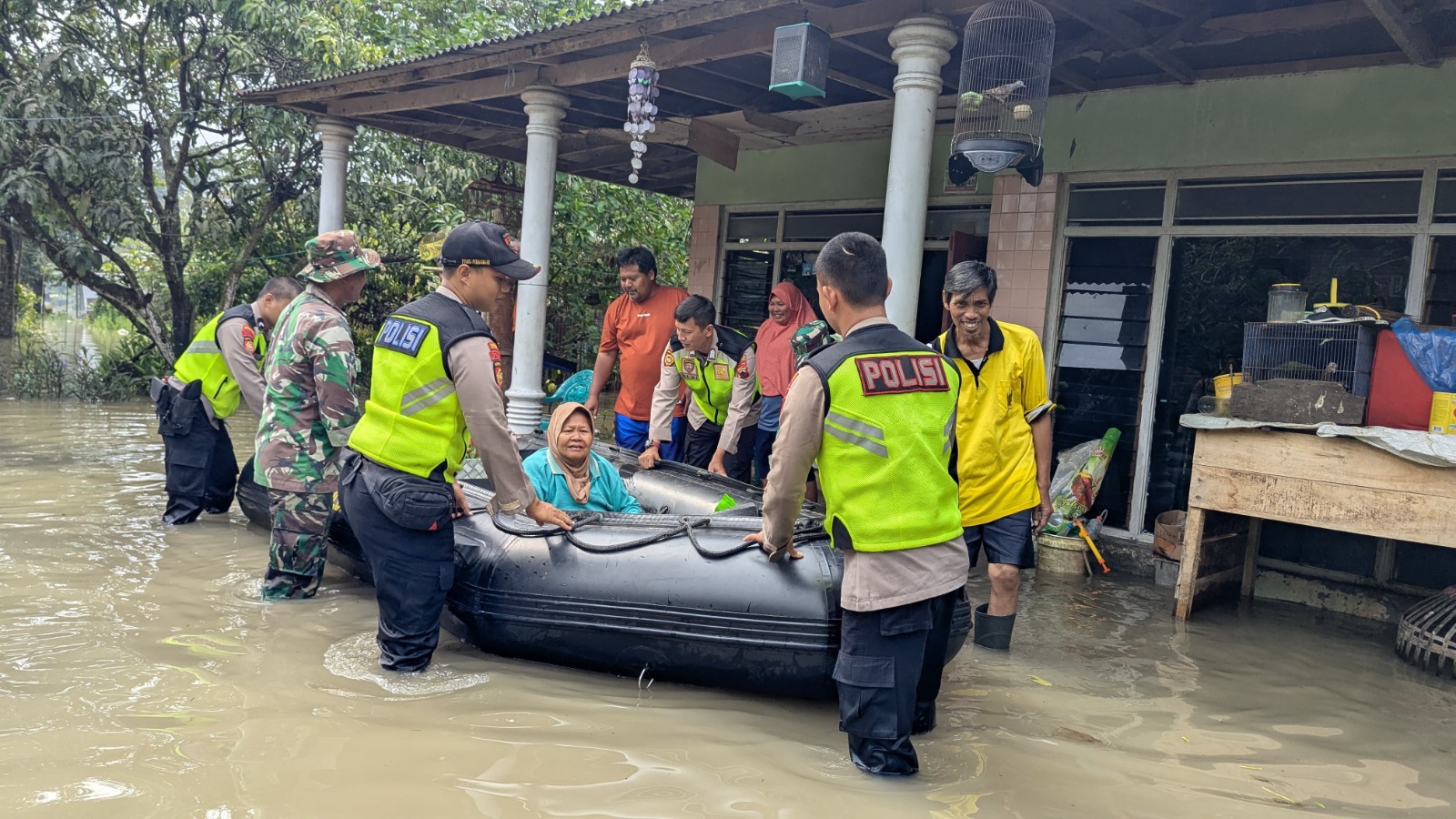 EVAKUASI: Polisi bersama Tim SAR gabungan saat mengevakuasi warga terdampak banjir di Desa Sipait, Kecamatan Siwalan, Kamis (5/2/2026) pagi.