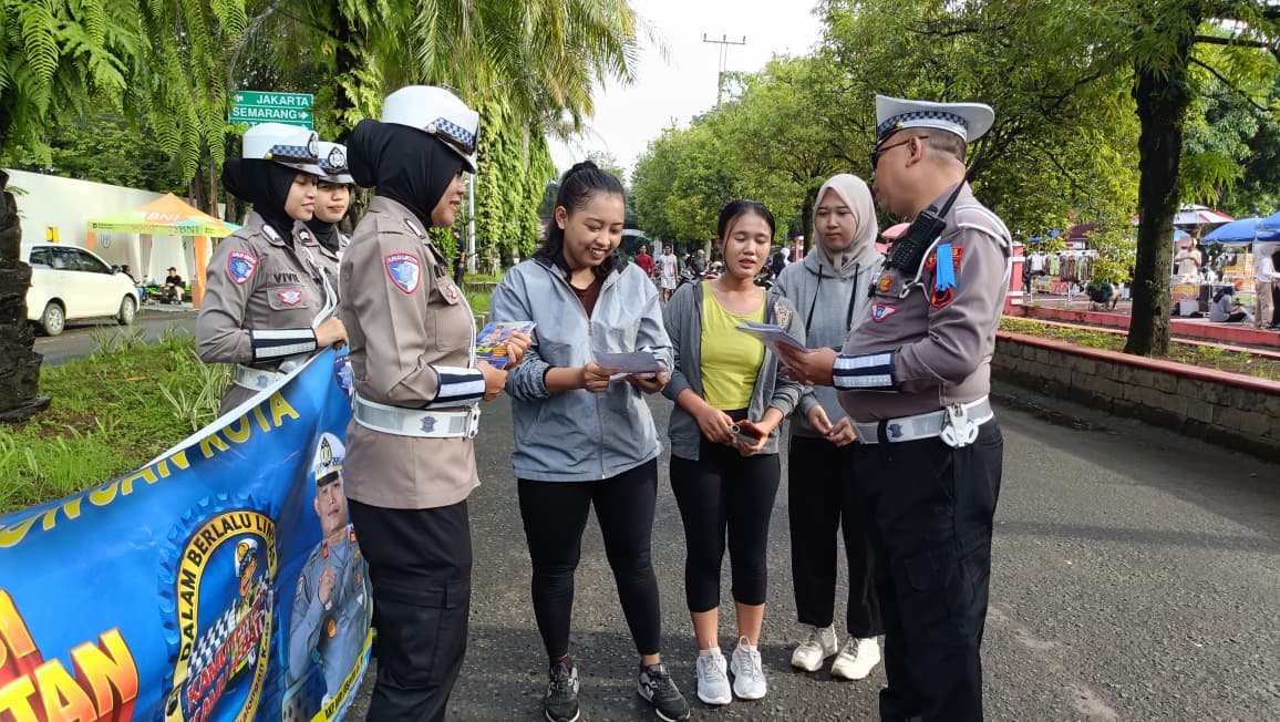 NGOBROL - Anggota Satlanstas Polres Pekalogan Kota saat ngobrol bersama warga yang sedang lari pagi&nbsp;di Lapangan Mataram Kota Pekalongan, Minggu (8/2/2026).