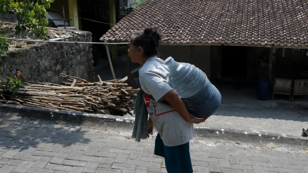 KEKERINGAN : Seorang warga Kelurahan Jabungan, Banyumanik menggendong galon berisi air bersih bantuan dari PMI Kota Semarang di Masjid Al-Hidayah Senin (3/8).  (FOTO : NUR CHAMIM/JAWA POS RADAR SEMARANG)