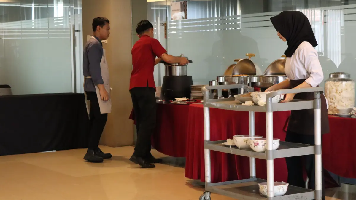 Catering staff prepare and organize food at a buffet station, serving dishes with a trolley in a modern indoor venue, showing teamwork and professional hospitality service, December 11, 2025