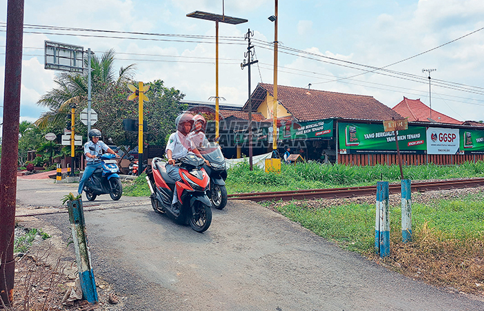 HATI-HATI : Beberapa pelajar sedang melewati perlintasan sebidang tanpa palang pintu di Kelurahan Tangkil, Kecamatan Wlingi, Senin (4/12/2023).