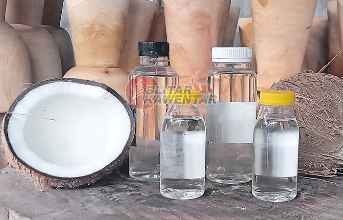 PROSES: Sumarmi menunjukkan proses pembuatan minyak kelapa dari mulai pemecahan kelapa hingga penyumbatan.