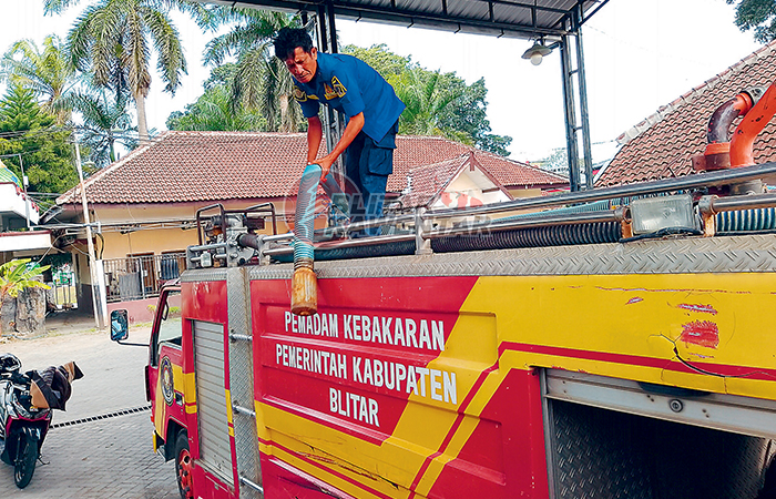 KURANG MUMPUNI: Salah seorang petugas damkar sedang melakukan perawatan salah satu unit mobil.