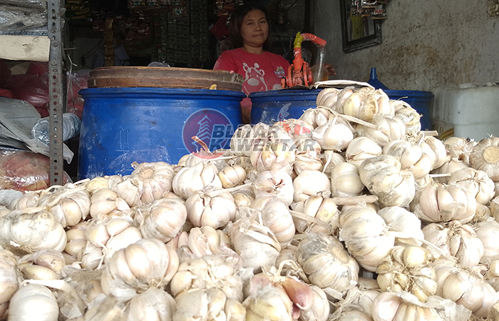 MENUMPUK: Suhartini menata dagangan bawang putihnya yang belakangan mengalami peningkatan harga cukup signifikan.
