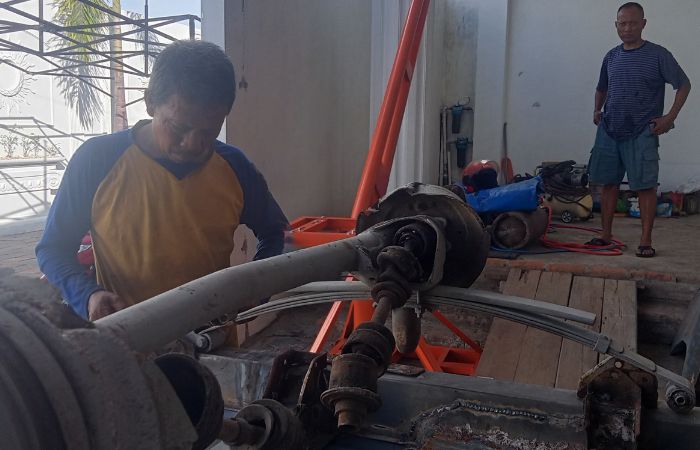 RAJIN: Seorang pekerja bengkel sedang melakukan reparasi kendaraan.