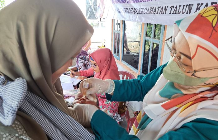 JANGAN NANGIS: Balita dalam gendongan orang tuanya menerima imunisasi polio.