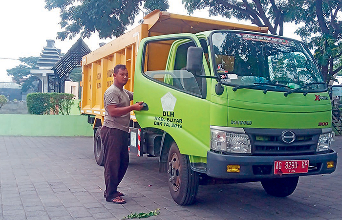 BERTUGAS: Petugas Dinas Lingkungan Hidup Kabupaten Blitar melintas di samping truk yang biasa digunakan untuk mengangkut ranting dan batang pohon.