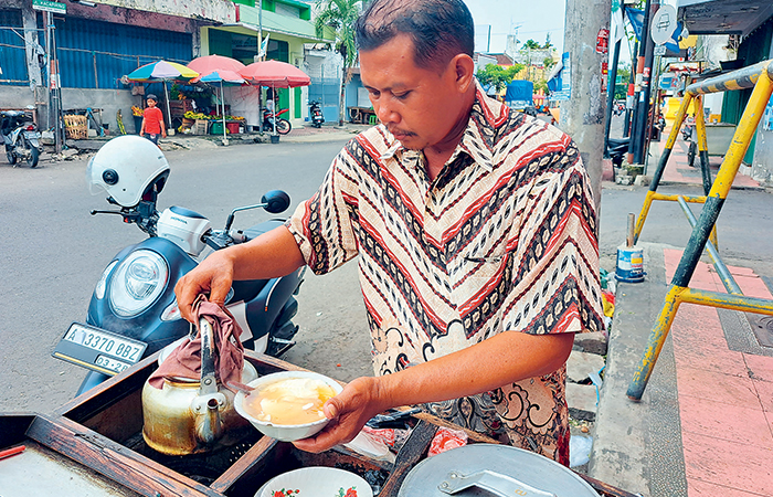 KONSISTEN: Waras sedang melayani pelanggannya di depan Pasar Templek Kota Blitar