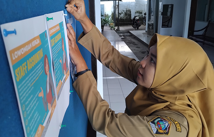 PELUANG: Pegawai Dinas Tenaga Kerja Kabupaten Blitar memasang flayer informasi magang di luar negeri.