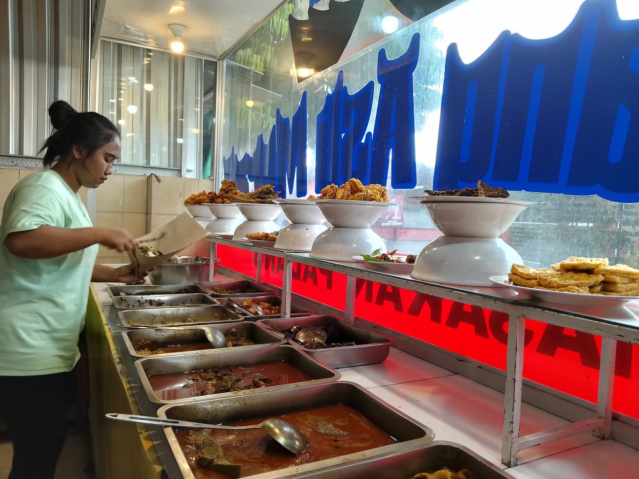 DEMI PELANGGAN: Pemilik warung mengambil lauk pauk untuk menu makan bagi pelanggan.