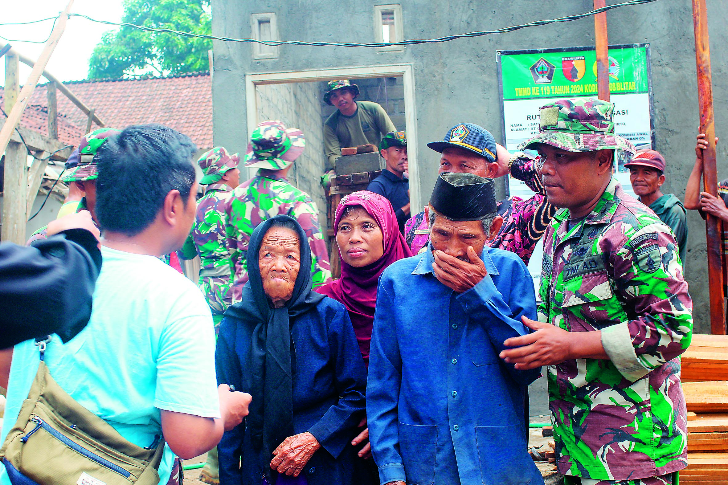 TERSENTUH: Dituntun tentara, kakek dan nenek tampak terharu ketika melihat bangunan rumahnya sebentar lagi jadi. Tentara dan warga saling bahu-membahu