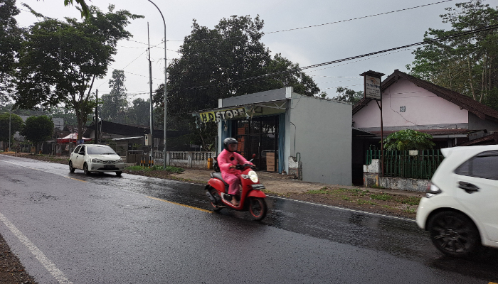 PERALIHAN CUACA: Pengendara motor mengenakan jas hujan saat melintas di jalan nasional wilayah Kecamatan Garum, kemarin (5/3).