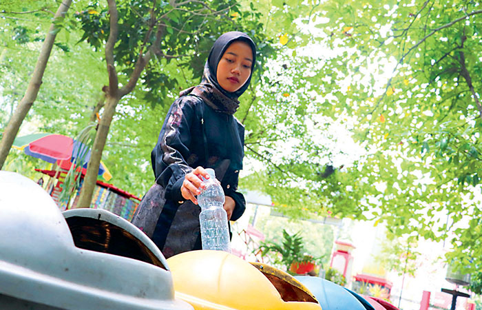 BLITAR JAGA LINGKUNGAN: Pengunjung Taman Kebon Rojo Kota Blitar membuang botol minuman plastik ke tempat sampah, kemarin (22/4).