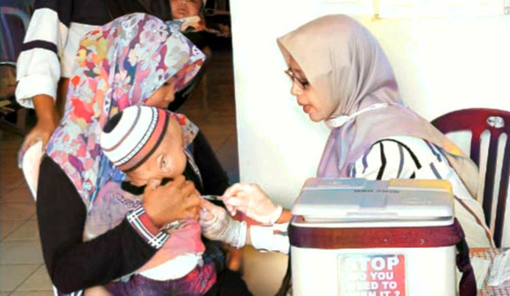 MENGGEMASKAN: Nakes memberikan suntikan vaksin pada bayi saat dalam gendongan ibunya. Awal tahun ini kasus Flu Singapura mayoritas didominasi anak-anak.