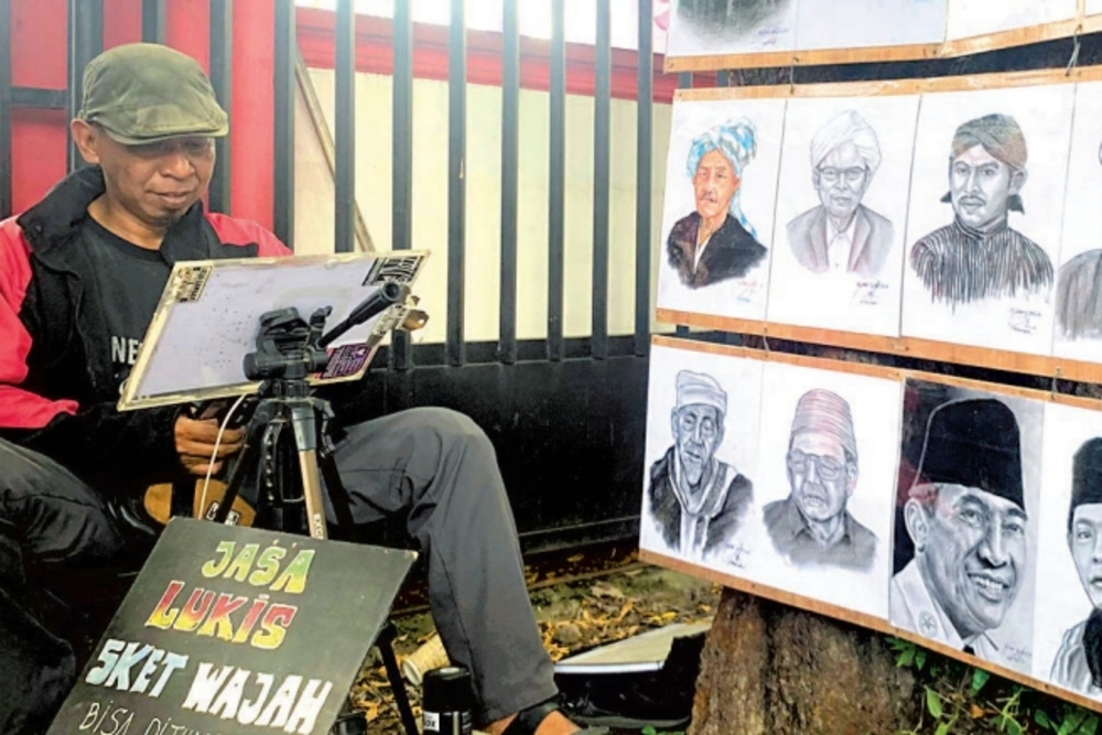 JIWA SENI: Suherman ketika mengerjakan pesanan lukisan berupa wajah beberapa waktu lalu.
