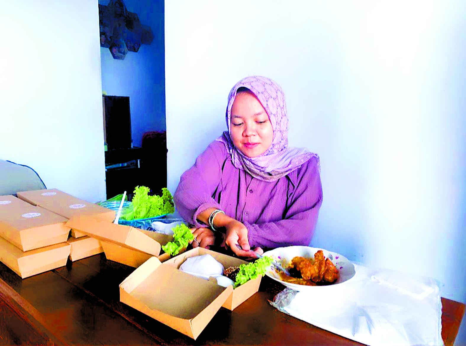 NIKMAT: Ervita Ayu Nur Atika mengemas nasi pesanan pelanggan,Senin (20/5).