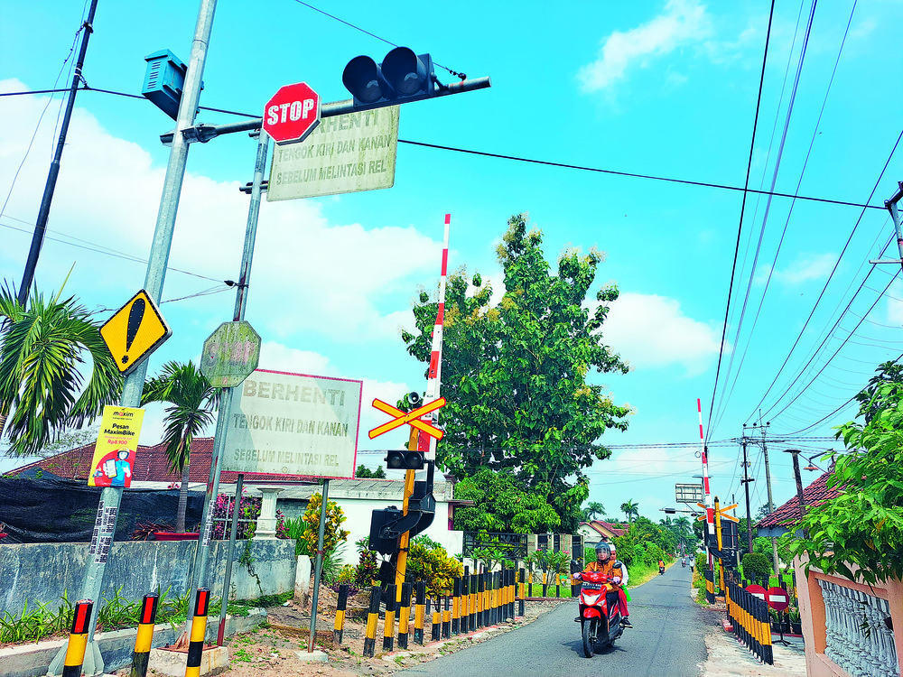 HATI-HATI: Pengendara motor melintasi perlintasan tanpa palang pintu di Kelurahan Sumberdiren, Kecamatan Garum. EWS di titik ini rusak.