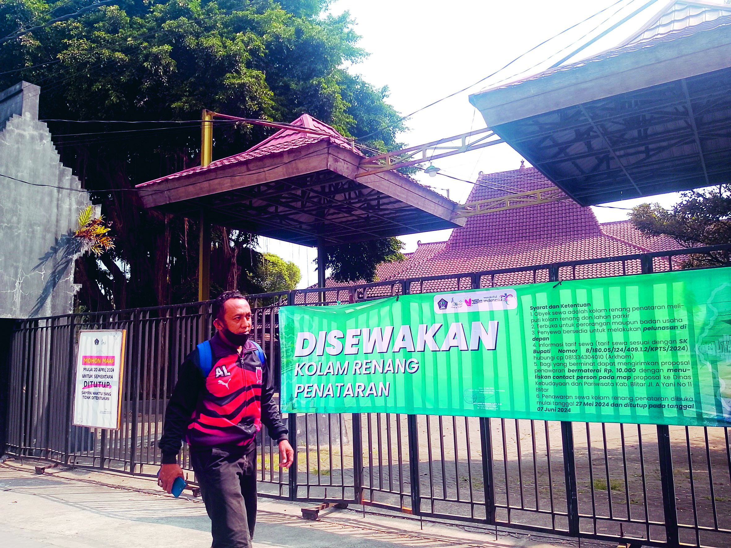 CARI PEMINAT: Warga sekitar berjalan di depan Kolam Renang Penataran yang sedang ditutup.&nbsp;