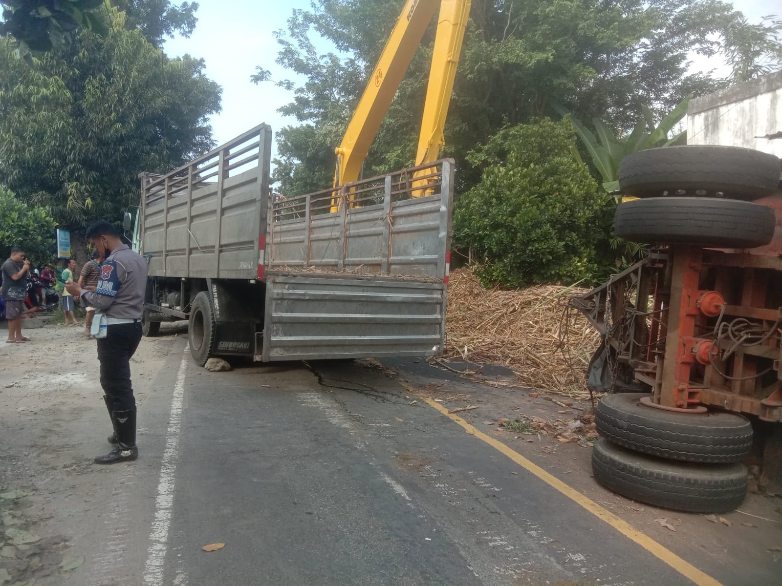 HARUS WASPADA: Polisi mengamankan proses evakuasi truk gandeng muatan tebu yang terguling saat melintasi tanjakan di Kelurahan Klemunan, Kecamatan Wlingi