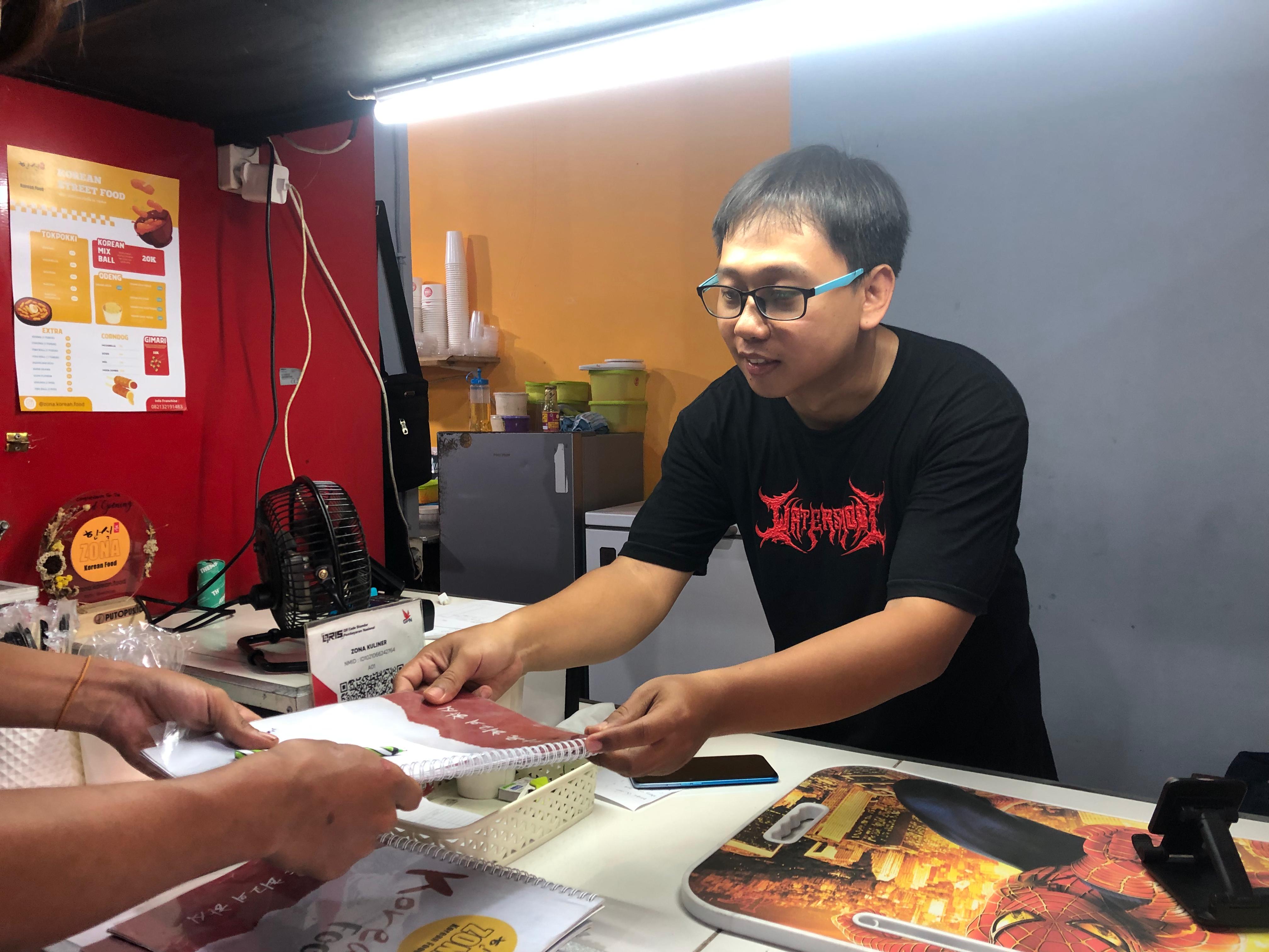 LAYANI PEMBELI: Owner kedai kuliner Korea, Panca Marfuan (berkacamata) menjelaskan menu pada pembeli, Rabu (19/6).