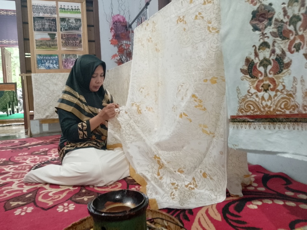 PILIH KAIN: Pembatik sedang menunjukkan proses mencanting di lembaran kain putih.