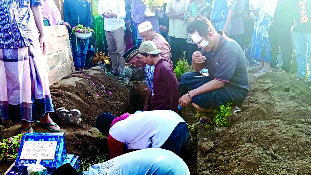 DUKA MENDALAM: Ali Mustofa (kanan), penumpang selamat, mengantar jenazah istri dan putra tercintanya, Imroatus Sholikah, hingga liang lahat, kemarin (23/6).