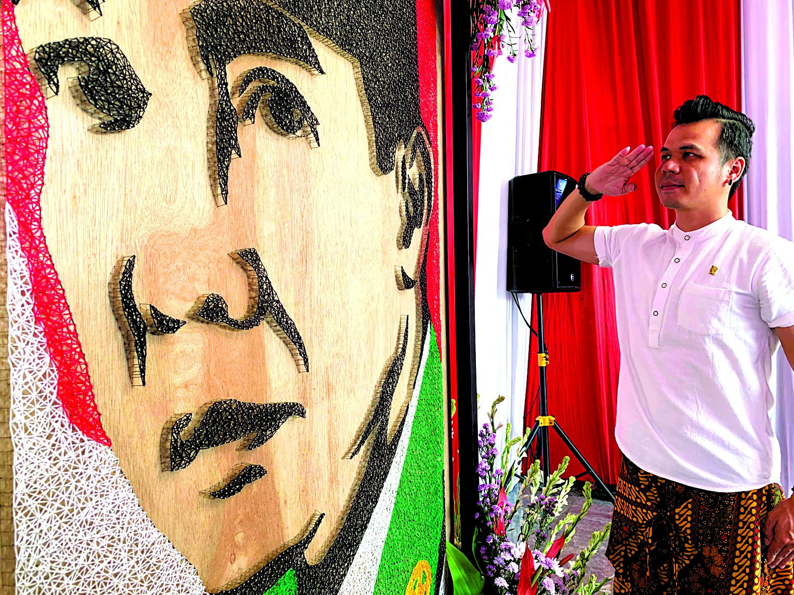 DARI HATI: Sofiyan alias Abang Seni berdiri hormat di depan karya lukis bergambar Bung Karno yang terbuat dari jarum pentul dan benang wol, Jumat (21/6) lalu.