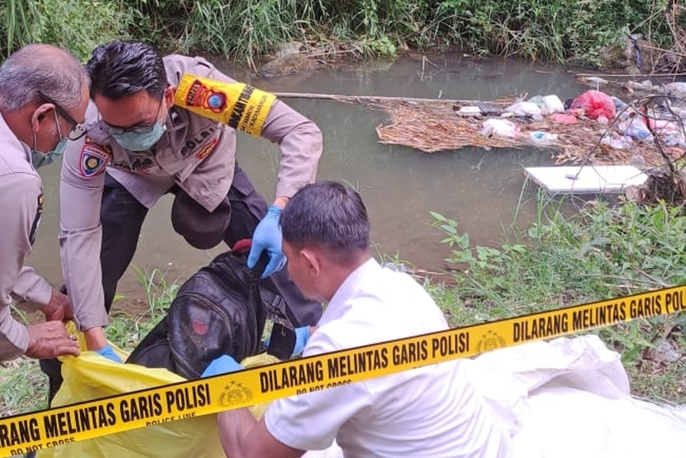 MENYENGAT: Polisi mengevakuasi orok bayi dari sungai di bawah jembatan Desa Jimbe, Selasa (9/7).