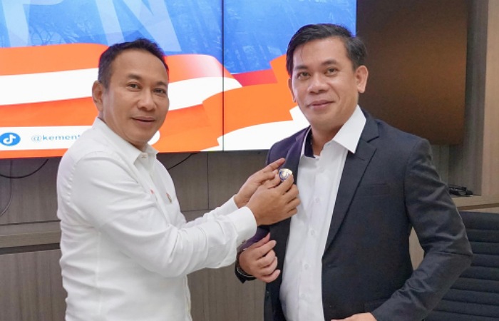 Lampri menyematkan pin kepada Kepala Biro Humas yang Baru, Harison Mocodompis simbol serah terima jabatan.
