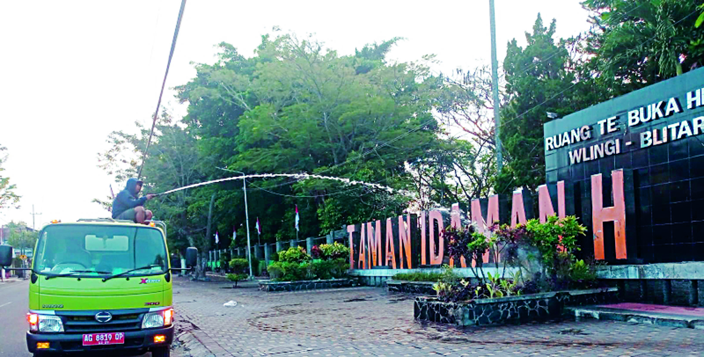 MENGUCUR: Petugas DLH Kabupaten Blitar menyiram tanaman di Taman Wlingi saat panas ekstrem.