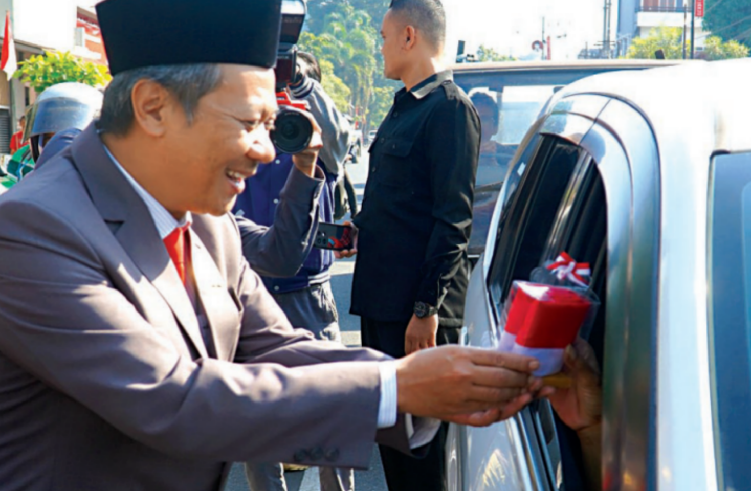NASIONALIS: Ketua DPRD Kota Blitar Syahrul Alim membagikan bendera merah putih kepada pengguna jalan, Jumat (16/8).