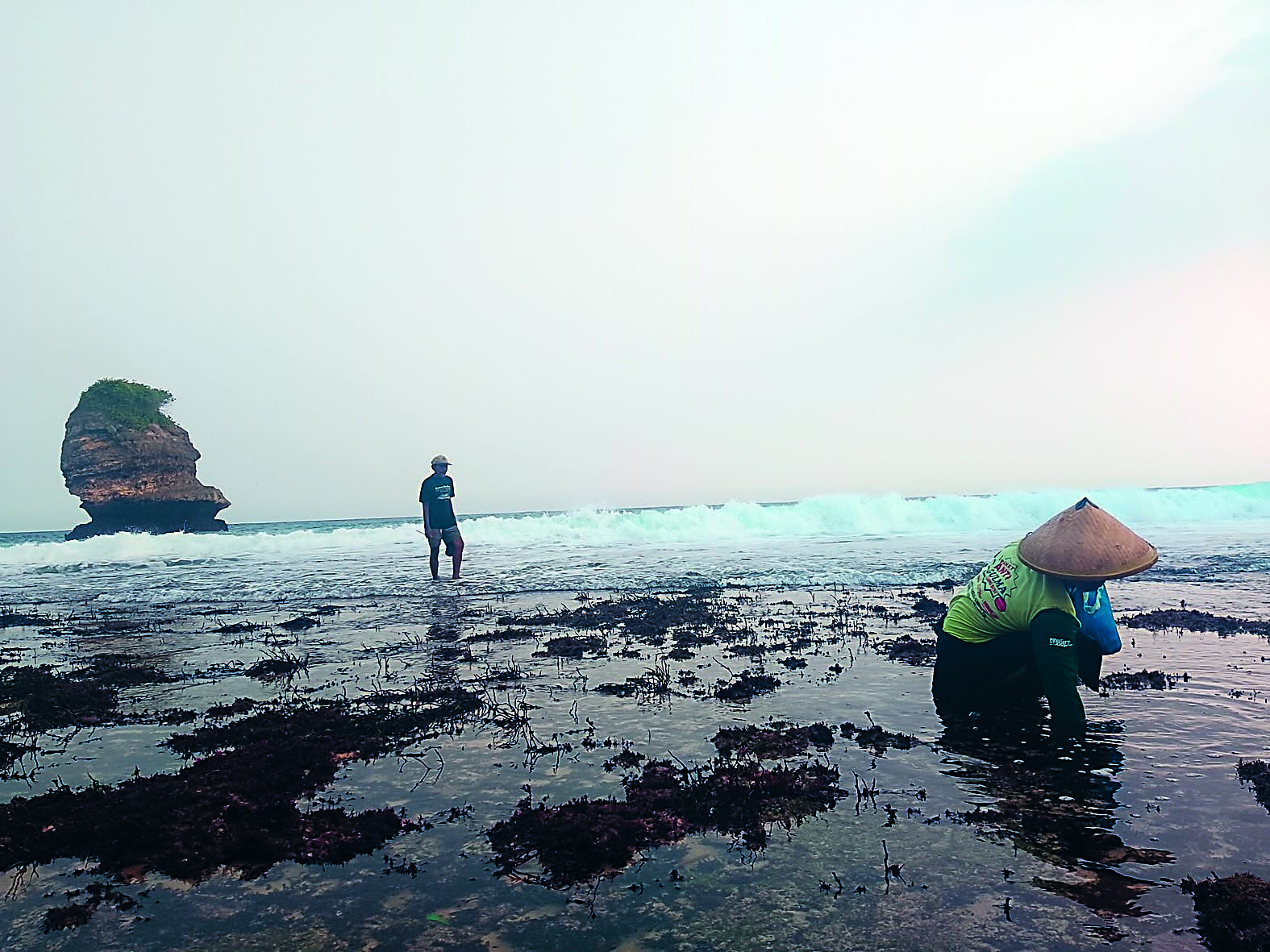 TAK MELAUT: Dua nelayan sedang berburu kerang di pesisir pantai saat cuaca ekstrem.