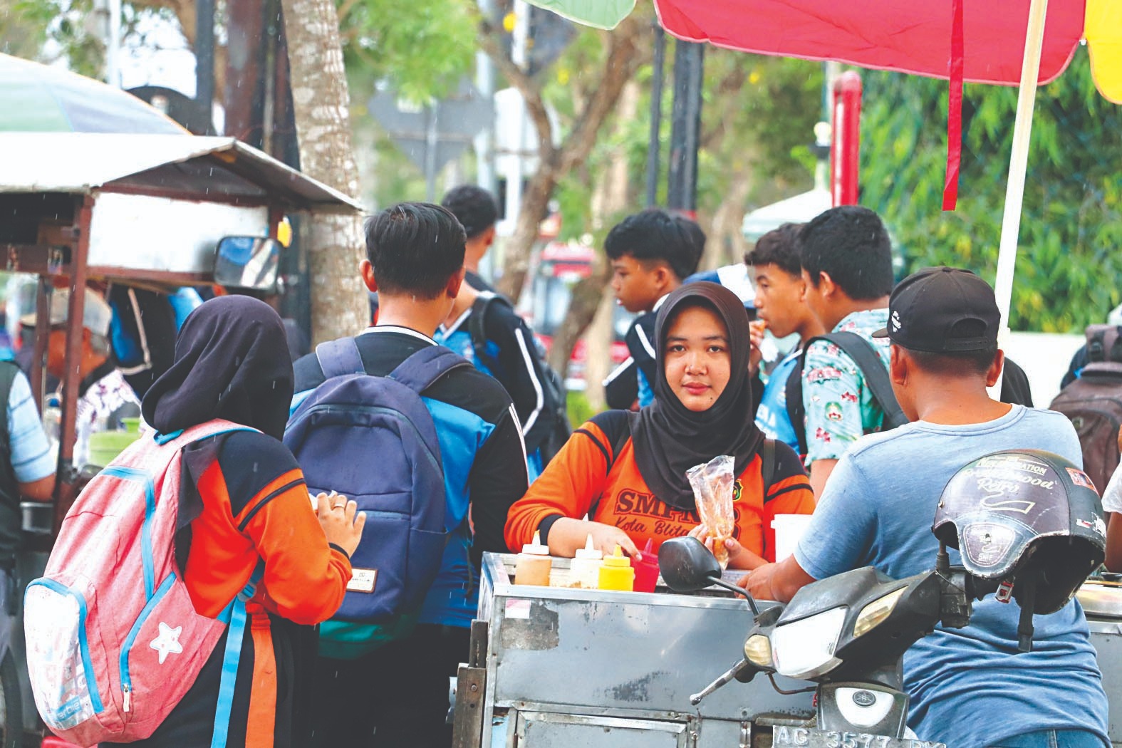 PERLU TELITI:  Beberapa  siswa sedang  membeli  jajanan di  luar sekolah  kemarin,  (30/10)