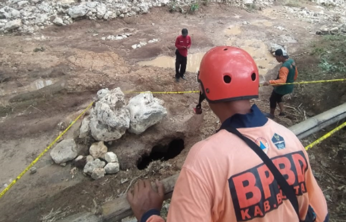 MISTERIUS: Warga melihat lubang berada di sungai Dusun Kaliandong, Desa Dawuhan, Kademangan, yang kini sudah dikasih garis polisi.