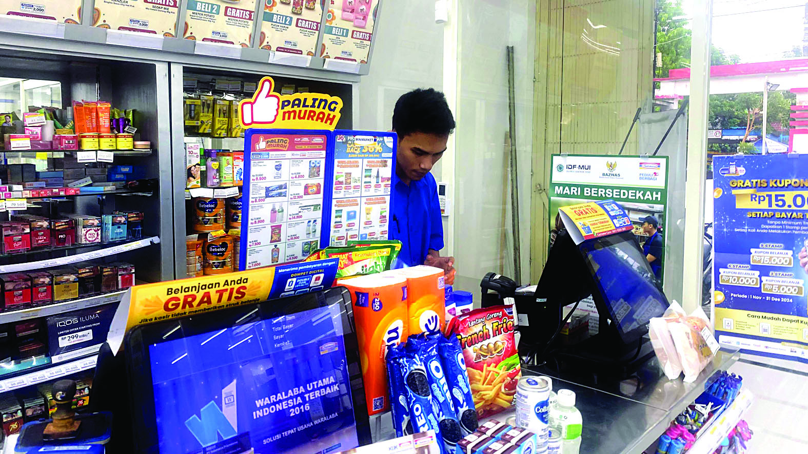 MELAYANI: Seorang kasir toko modern berjejaring tengah melayani pembeli beberapa waktu lalu.
