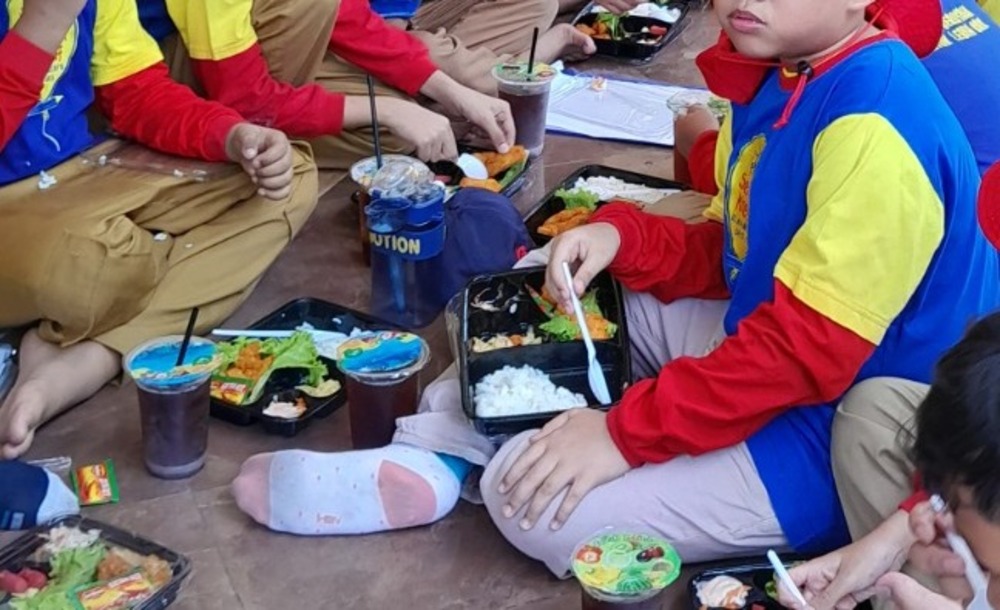 Siswa sekolah dasar yang sedang makan siang di luar kelas