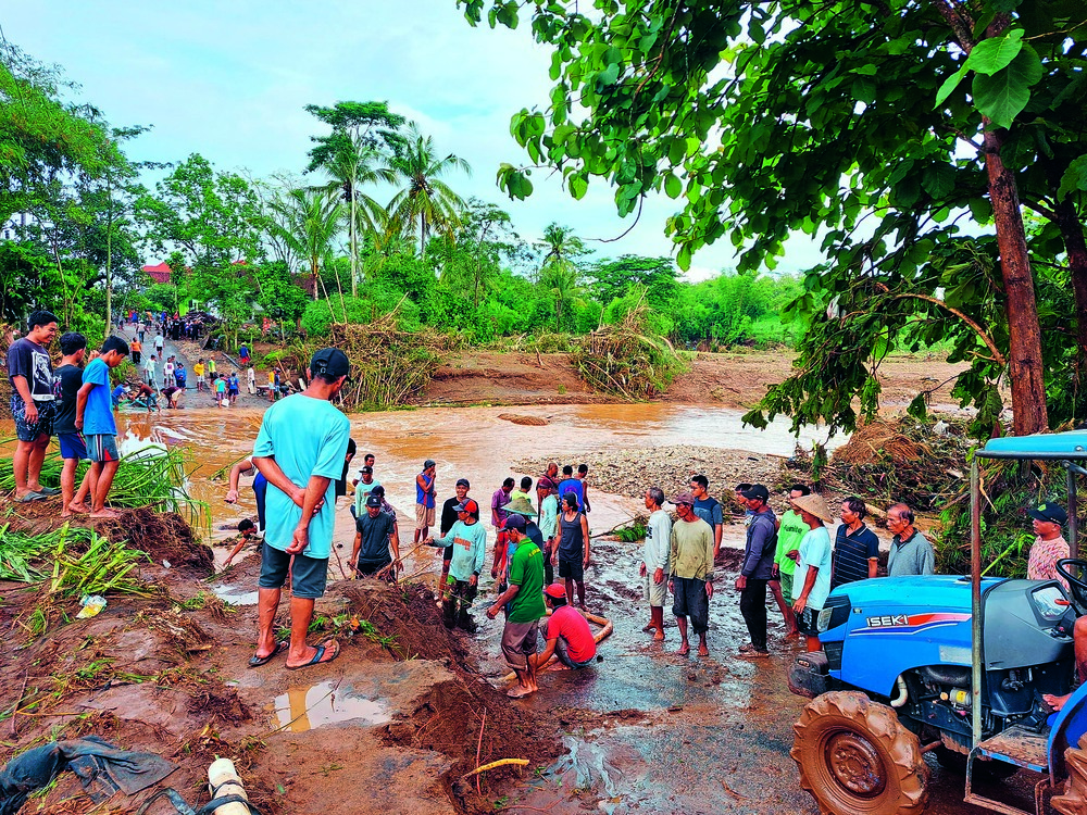 GOTONG-ROYONG : Masyarakat Desa Sambigede saling bantu membesihkan material banjir di sabo dam yang menjadi akses jalan bagi warga dua 2 dusun di desa tersebut, kemarin (1/12).