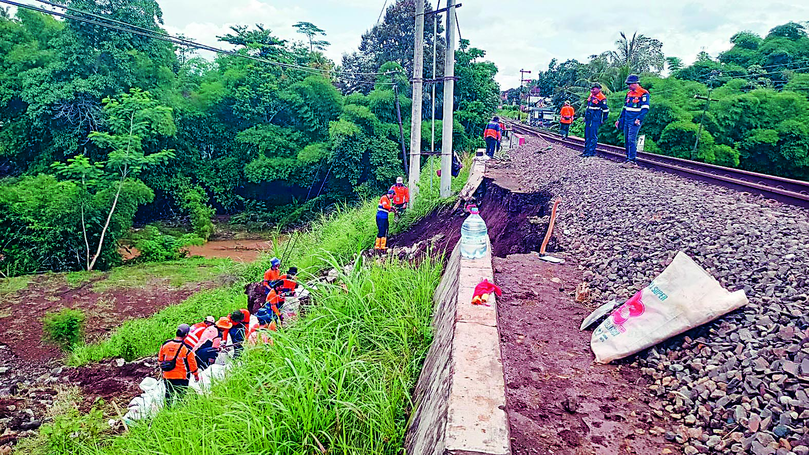 EVAKUASI : Petugas KAI melakukan pembersihan material banjir dan longsor untuk menormalisasi jalur kereta api, kemarin (1/12).