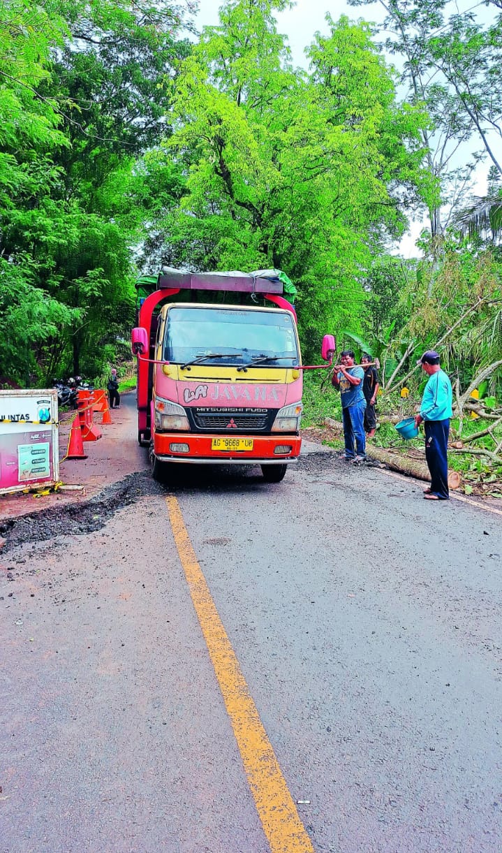 BERBAHAYA: Truk melintas di jalan nasional Blitar-Malang yang retak dan ambles akibat hujan deras beberapa hari terakhir.