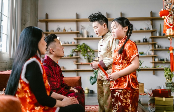 Potret keluarga Tionghoa yang merayakan Imlek dan orang tua yang membagikan angpao kepada anak-anaknya