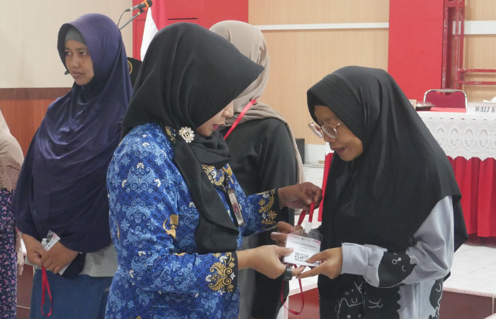 Kepala Dinsos Kota Blitar, Sad Sasmintarti mengalungkan kartu Rastrada Non Tunai kepada KPM.